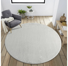 Vardagsrum med rund matta, fåtölj och sidobord.