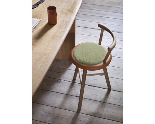 Träpall med rund sittdyna och ryggstöd bredvid ett bord.