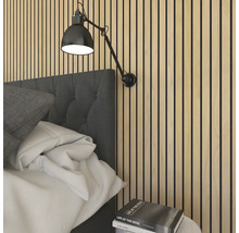 Sovrum med akustikpaneler på väggen och en justerbar vägglampa ovanför sängen