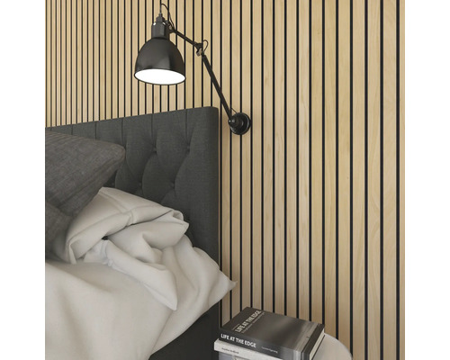 Sovrum med akustikpaneler på väggen och en justerbar vägglampa ovanför sängen