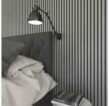 Sovrum med säng, vägglampa och nattduksbord med bok