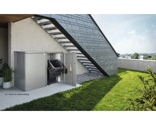 Metallåda för soptunnor med soptunna och trädgårdsredskap mot en husvägg med extern trappa