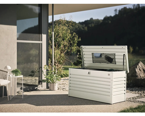 Öppen trädgårdsbox i metall på en terrass med utsikt över trädgården