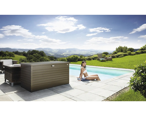 Scen med en förvaringslåda i metall bredvid en pool, omgiven av trädgårdsmöbler och en kvinna som sitter i vattnet.