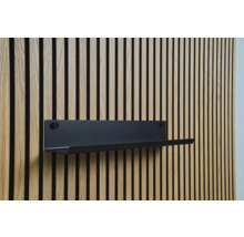 Svart vägghylla på en träpanelvägg