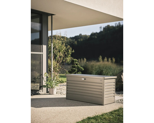 Trädgårdskista i metall på en terrass framför ett modernt hus