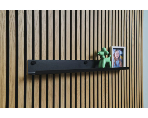 Svart vägghylla framför en träpanelvägg med dekoration