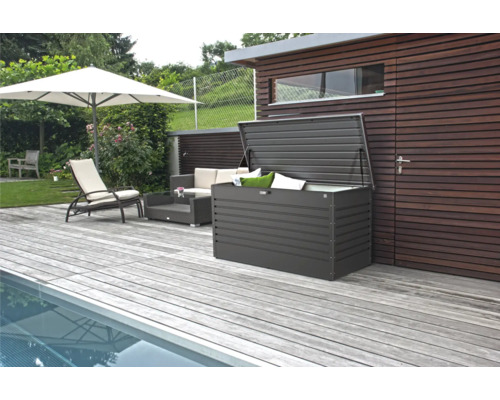 Trädgårdsscen med pool, uteplats, parasoll, loungemöbler och en öppen förvaringslåda