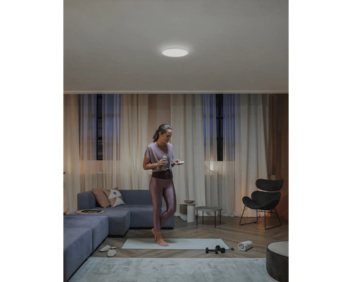 Kvinna som sportar i vardagsrummet med taklampa