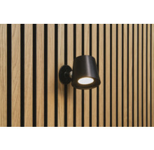 Svart vägglampa på en vägg med träpaneler