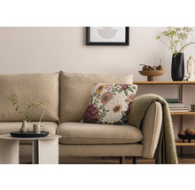 Vardagsrumsscen med beige soffa, blommönstrad prydnadskudde och sidobord