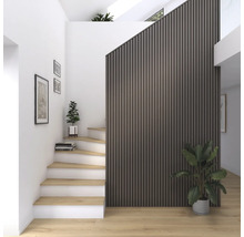 Ljus hall med trappa, väggpaneler och krukväxter.