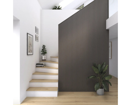 Ljus hall med trappa, väggpaneler och krukväxter.