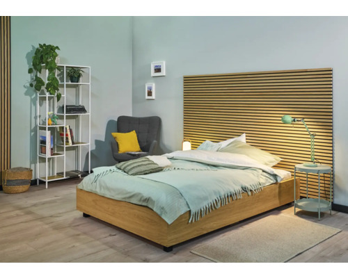 Ljust sovrum med säng, sängbord, hylla och fåtölj