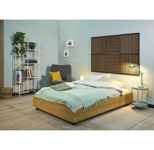 Ljust sovrum med säng, sängbord, lampa, fåtölj, hylla och väggpanel för en vänlig atmosfär