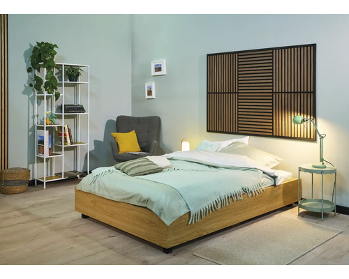 Sovrum med säng, sängbord, lampa, fåtölj, hylla och väggpanel