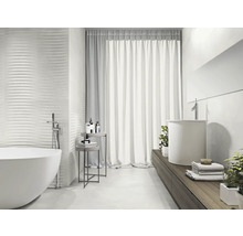 Ljust badrum med fristående badkar, handfat och strukturerade väggplattor för en modern design.