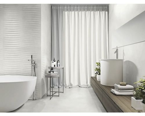 Ljust badrum med fristående badkar, handfat och strukturerade väggplattor för en modern design.