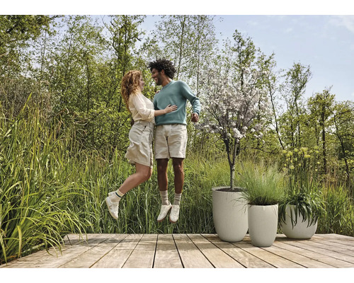 Scen med par på trädäck bredvid strukturerade planteringar och trädgård