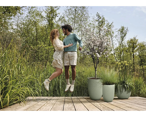 Ett par hoppar på en träaltan bredvid tre planteringar.