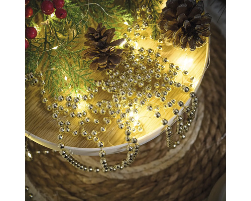 Dekoration med grangrenar, kottar och guldfärgad kulkedja