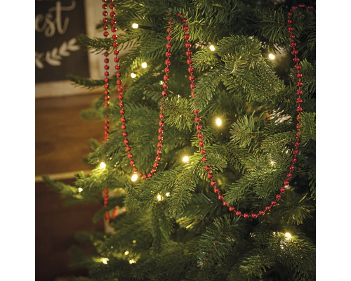 Dekorerad julgran med röd pärlkedja och belysning