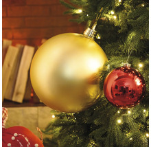 Närbild av en julgran med guld- och röda julgranskulor och ljus