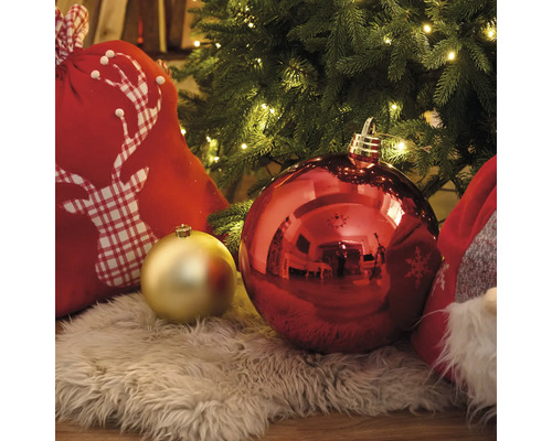 Juldekoration med julgranskulor, presentsäck med hjortmotiv och ljusslinga under julgranen