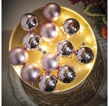 Dekorativa julkulor i rosa på en träbricka med ljus