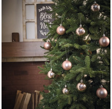 Dekorerad julgran med kulor framför öppen spis