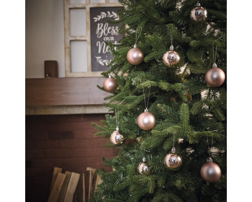 Dekorerad julgran med kulor framför öppen spis