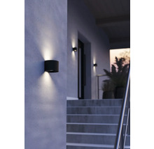 Utomhusvägglampa i cylindrisk form ger ljus på en husvägg