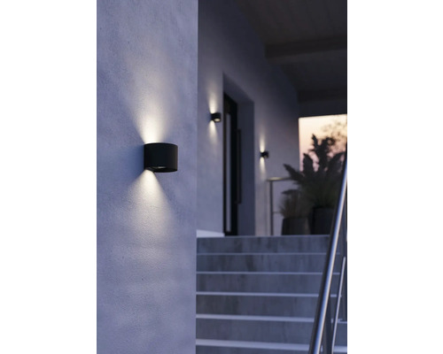 Utomhusvägglampa i cylindrisk form ger ljus på en husvägg