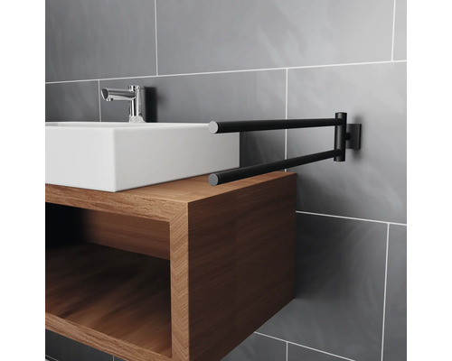 Tvättställ med armatur på träunderskåp och svängbar handdukshållare på grå vägg