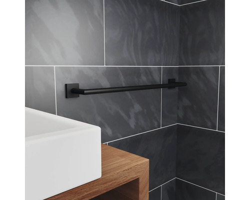 Svart handdukshängare i badrum med handfat och gråa kakelplattor