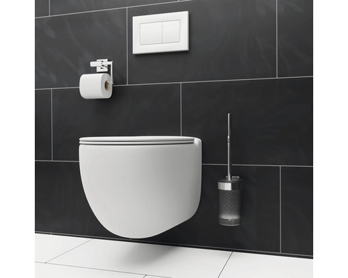Vägghängd toalett med toalettpappershållare, manöverpanel och toalettborste mot en mörk kakelbakgrund.