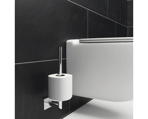 Vägghängd toalett bredvid en toalettpappershållare i badrummet.