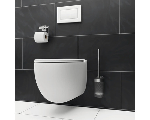 Vägghängd toalett med spolplatta, toalettpappershållare och toalettborste på en vägg med kakel