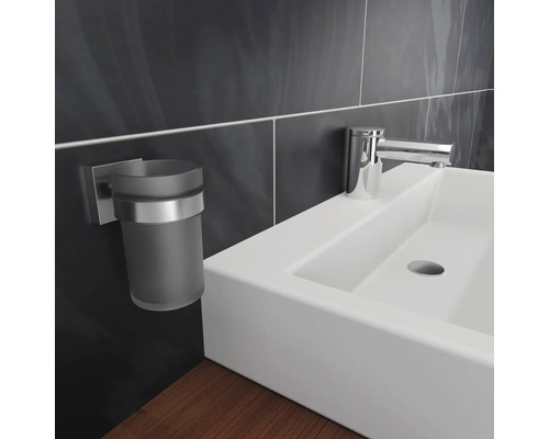 Detaljbild av ett handfat med kran och tandborstmuggshållare i badrummet