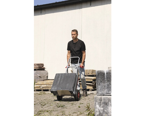 Man transporterar gatsten med en säckkärra.
