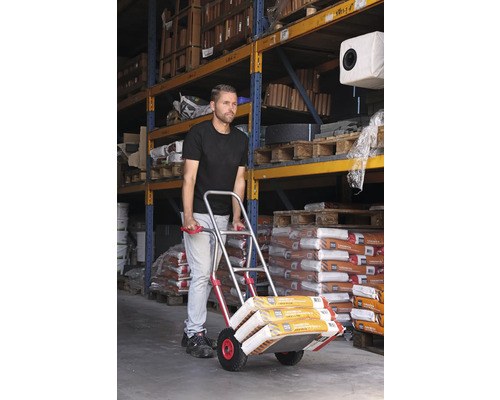 Man transporterar säckvaror med en säckkärra i ett lager.