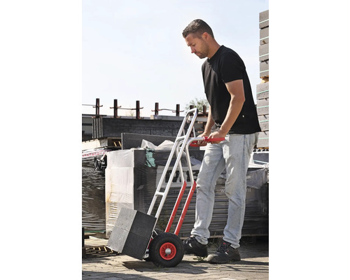 Man transporterar gatsten med en säckkärra.