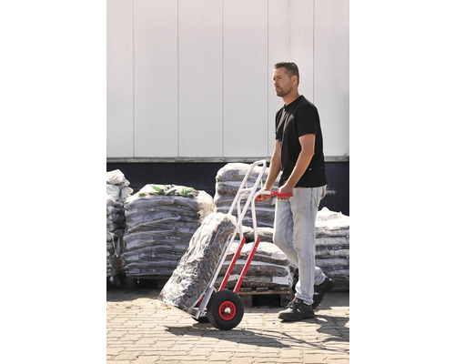 Man transporterar säckar med en säckvagn framför ett lager