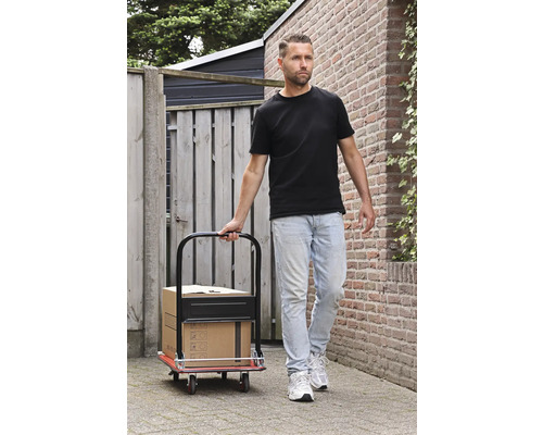 Man drar en säckkärra med kartonger på en stenlagd väg