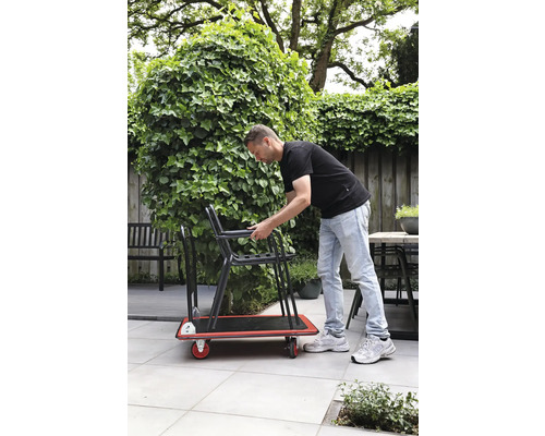 Man transporterar stolar på en rullbräda i trädgården