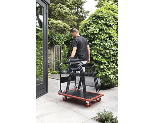 En person transporterar stolar i trädgården med en rullbräda.