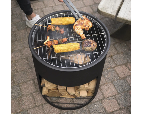 "En kolgrill med grillad mat som kyckling, majskolvar och köttspett vänds med en grilltång