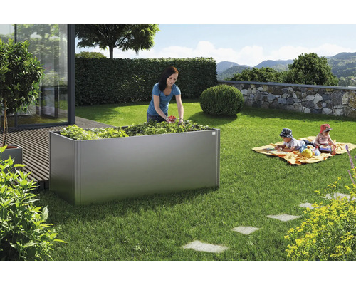 Hög rabatt i trädgården med kvinna som skördar och barn som leker