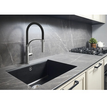 Köksscen med diskho, armatur, spishäll och bänkskiva i modern design.