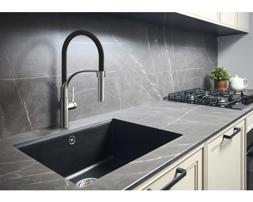Köksscen med diskho, armatur, spishäll och bänkskiva i modern design.